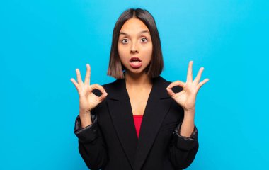 İspanyol kadın şok olmuş, şaşırmış ve şaşırmış hissediyor. Onaylıyor. İki eliyle işaret veriyor.