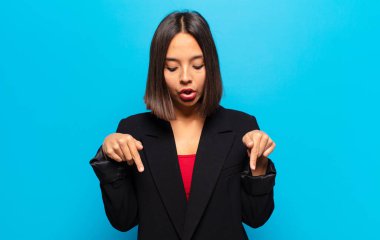 İspanyol kadın şok olmuş, ağzı açık ve şaşırmış hissediyor. İnançsızlık ve şaşkınlık içinde bakıyor ve onu işaret ediyor.