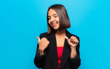 İspanyol kadın neşeli bir şekilde gülümsüyor ve yan taraftaki fotokopi alanını gösteriyor, mutlu ve tatmin olmuş hissediyor.