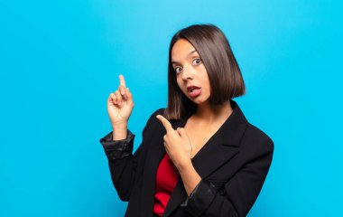 İspanyol kadın şaşkın ve şaşırmış hissediyor. Kenardaki fotokopi alanını işaret ediyor. Şaşırmış, ağzı açık bir bakışla.