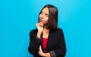 Hispanik kadın düşünceli, meraklı ya da hayal kuruyor, hayal kuruyor ve mekanı kopyalamak için yukarı bakıyor.