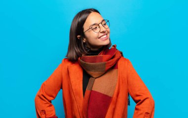 İspanyol kadın mutlu, neşeli ve kendinden emin görünüyor. Gururla gülümsüyor ve iki elini de kalçasında istiyor.