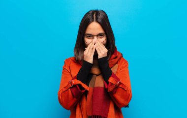 İspanyol kadın mutlu, neşeli, şanslı ve şaşkın görünüyor. İki eliyle ağzını kapatıyor.