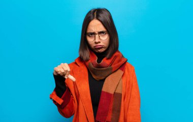 Hispanik kadın kızgın, sinirli, hayal kırıklığına uğramış ya da hoşnutsuz, ciddi bir bakışla başparmaklarını göstermiyor.