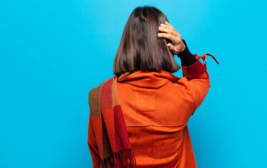 Hispanik kadın düşünüyor ya da şüphe ediyor, kafasını kaşıyor, şaşkın ve şaşkın hissediyor, arkaya ya da arkaya bakıyor.