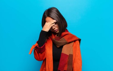 İspanyol kadın stresli, utanmış ya da üzgün görünüyor, baş ağrısı var, yüzünü elleriyle kapatıyor.