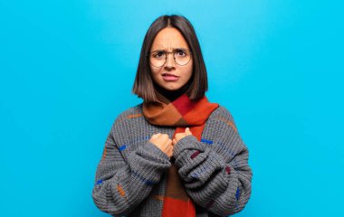 İspanyol kadın şaşkın ve şaşkın bir bakışla kendini işaret ediyor. Seçildiğine şaşırmış ve şaşırmış.