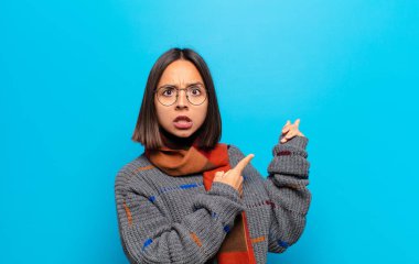 İspanyol kadın şaşkın ve şaşırmış hissediyor. Kenardaki fotokopi alanını işaret ediyor. Şaşırmış, ağzı açık bir bakışla.