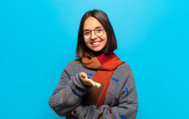 İspanyol kadın gülümsüyor, mutlu görünüyor, kendinden emin ve arkadaş canlısı, bir anlaşma yapmak için el sıkışma teklif ediyor, işbirliği yapıyor.