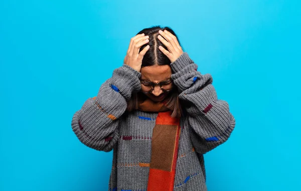 İspanyol kadın kendini stresli ve hayal kırıklığına uğramış hissediyor, elele tutuşuyor, yorgun, mutsuz ve migren ağrısı çekiyor.