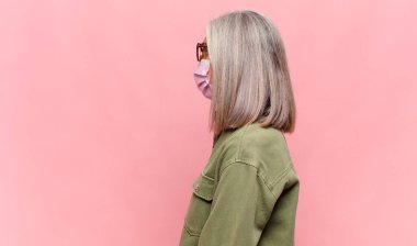 Profil görünümlü orta yaşlı kadın ileriyi kopyalamak istiyor, düşünüyor, hayal ediyor ya da hayal kuruyor.