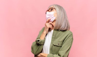 Orta yaşlı kadın düşünüyor, kuşkulu ve şaşkın hissediyor, farklı seçeneklerle, hangi kararı vereceğini merak ediyor.