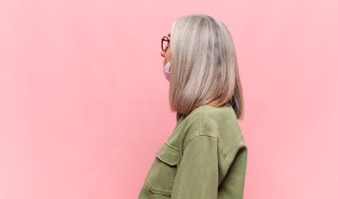 Profil görünümlü orta yaşlı kadın ileriyi kopyalamak istiyor, düşünüyor, hayal ediyor ya da hayal kuruyor.