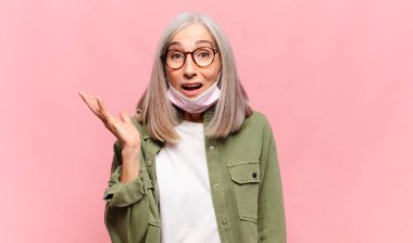 Orta yaşlı bir kadın mutlu, şaşırmış ve neşeli, pozitif bir tavırla gülümsüyor, bir çözüm ya da fikir buluyor.