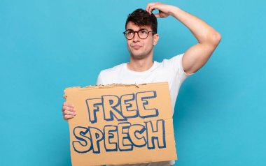 Genç adam şaşkın ve şaşkın hissediyor, başını kaşıyor ve yana bakıyor.