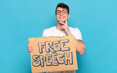 Genç adam mutlu bir şekilde gülümsüyor ve hayal kuruyor ya da şüphe ediyor.