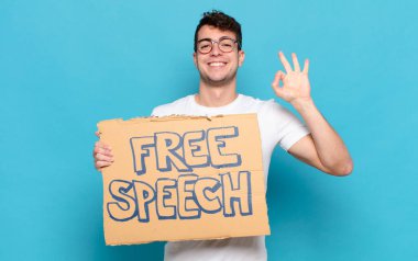 Genç adam mutlu, rahat ve tatmin olmuş hissediyor. Onayını iyi bir hareketle gösteriyor. Gülümsüyor.