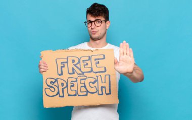 Genç adam ciddi, sert, hoşnutsuz ve kızgın görünüyor. Avuç içinin açık olması jesti durduruyor.