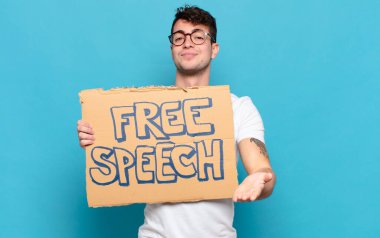 Genç adam mutlu bir şekilde gülümsüyor arkadaş canlısı, kendinden emin, pozitif bakışlı, bir nesne ya da konsept sunuyor ve gösteriyor