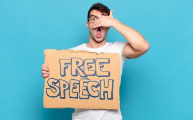 Genç adam şok olmuş, korkmuş ya da korkmuş görünüyor. Yüzü elle örtülmüş ve parmaklarının arasından gizlice bakıyor.