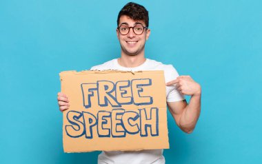 Genç adam mutlu, şaşkın ve gururlu, heyecanlı, şaşkın bakışlarla kendini işaret ediyor.