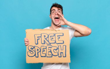 Genç adam mutlu, heyecanlı ve pozitif hissediyor. Elleri ağızda, bağırıyor.