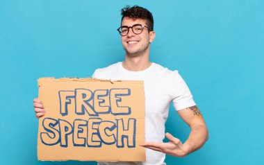 Genç adam neşeyle gülümsüyor, mutlu hissediyor ve bir konsepti fotokopi uzayında el ele vererek gösteriyor.