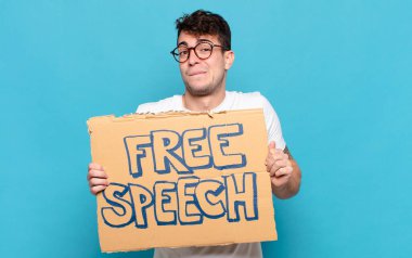 Genç adam şaşkın ve şaşkın görünüyor, gergin bir hareketle dudağını ısırıyor, sorunun cevabını bilmiyor.