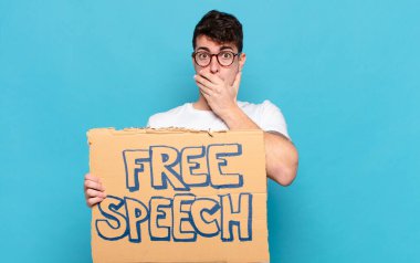 Delikanlı elleri ile ağzını kapatıyor, şok olmuş, şaşırmış bir ifadeyle, sır saklıyor ya da 