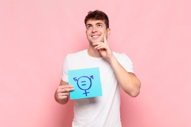 Genç adam mutlu bir şekilde gülümsüyor ve hayal kuruyor ya da şüphe ediyor.