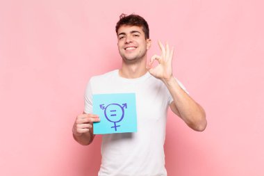 Genç adam mutlu, rahat ve tatmin olmuş hissediyor. Onayını iyi bir hareketle gösteriyor. Gülümsüyor.