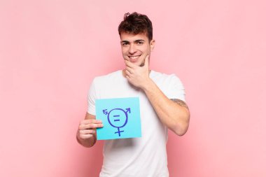 Genç adam mutlu, kendinden emin bir ifadeyle gülümsüyor, çenesinde elleri olan, merak eden ve yan tarafa bakan