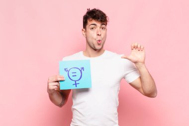 Genç adam inançsızlıktan şaşkın şaşkın bakıyor, yan taraftaki objeyi işaret ediyor ve diyor ki: