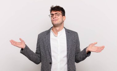 Genç adam şaşkın ve şaşkın hissediyor, şüpheci, farklı seçenekleri tartıyor veya komik bir ifadeyle seçiyor.