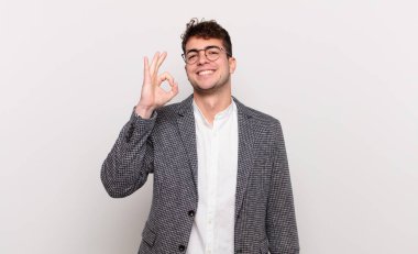 Genç adam mutlu, rahat ve tatmin olmuş hissediyor. Onayını iyi bir hareketle gösteriyor. Gülümsüyor.