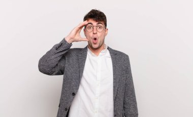 Genç adam mutlu, şaşkın ve şaşırmış görünüyor, gülümsüyor ve inanılmaz ve inanılmaz iyi haberleri fark ediyor.