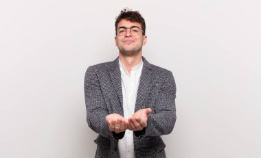 Genç adam mutlu bir şekilde gülümsüyor arkadaş canlısı, kendinden emin, pozitif bakışlı, bir nesne ya da konsept sunuyor ve gösteriyor