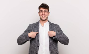 Genç adam mutlu, şaşkın ve gururlu, heyecanlı, şaşkın bakışlarla kendini işaret ediyor.