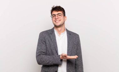 Genç adam neşeyle gülümsüyor, mutlu hissediyor ve bir konsepti fotokopi uzayında el ele vererek gösteriyor.