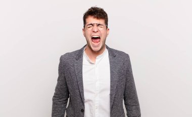 Genç adam agresif bir şekilde bağırıyor, çok kızgın, hayal kırıklığına uğramış, öfkeli ya da sinirli görünüyor.