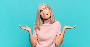 Orta yaşlı kadın şaşkın ve şaşkın hissediyor, şüpheci, farklı seçenekleri tartıyor veya komik bir ifadeyle seçiyor.