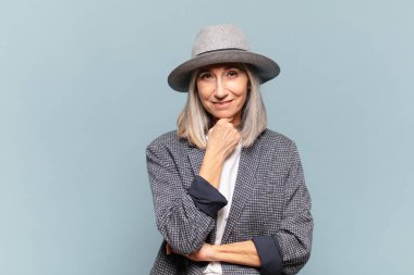 Orta yaşlı kadın gülümsüyor, hayattan zevk alıyor, mutlu, arkadaş canlısı, tatmin olmuş ve tasasız.