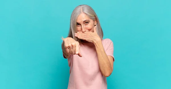 middle age woman laughing at you, pointing to camera and making fun of or mocking you
