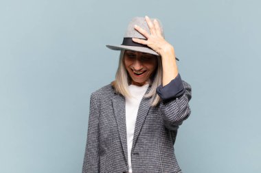 Orta yaşlı bir kadın gülüyor ve alnına şaplak atıyor. Unuttum ya da aptalca bir hataydı. 