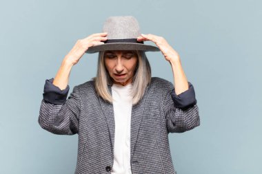 Stresli ve hayal kırıklığına uğramış görünen orta yaşlı bir kadın, baskı altında çalışıyor, başı ağrıyor ve sorunları var.