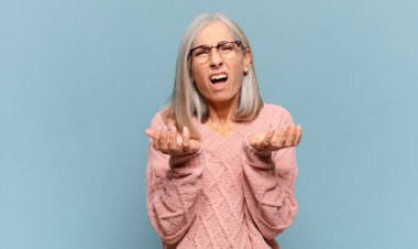 Orta yaşlı kadın umutsuz ve sinirli görünüyor, stresli, mutsuz ve sinirli, bağırıyor ve çığlık atıyor.