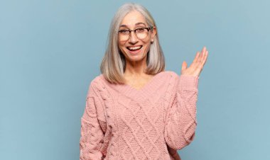 Orta yaşlı bir kadın mutlu, şaşırmış ve neşeli, pozitif bir tavırla gülümsüyor, bir çözüm ya da fikir buluyor.