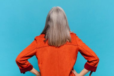 Orta yaşlı bir kadın kafası karışık ya da dolgun ya da şüphe ve soru dolu, merak ediyor, elleri kalçasında, dikiz aynasından.