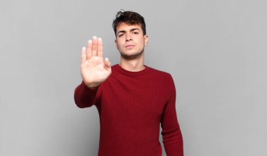 Genç adam ciddi, sert, hoşnutsuz ve kızgın görünüyor. Avuç içinin açık olması jesti durduruyor.