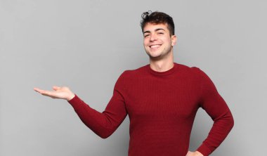 Genç adam gülümsüyor, kendinden emin, başarılı ve mutlu, fotokopi alanında fikir veya konsept gösteriyor.